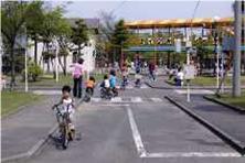 子供たちが自転車に乗って遊んでいる交通公園内の写真